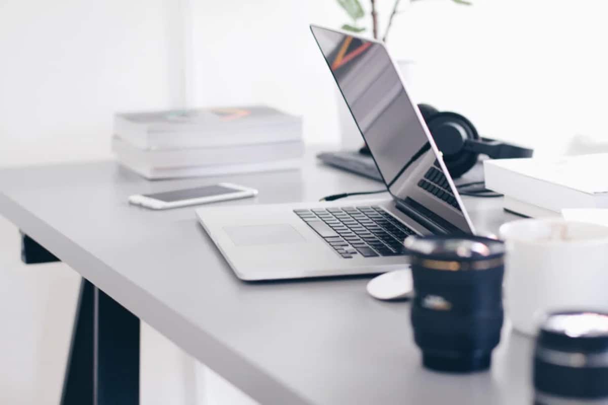 A laptop, phone, and notebooks on a clean white desk, ready for planning